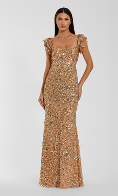A woman stands against a plain light background wearing the Mac Duggal 94279 Long Formal Dress in Gold Nude, which features short ruffled sleeves, a square neckline, and a floor-length silhouette adorned with sequins.