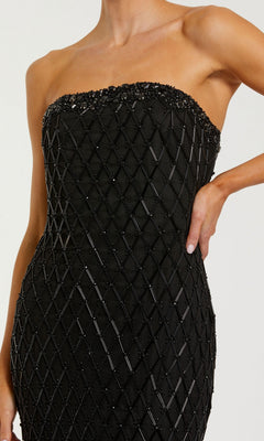 A woman showcases the Tea-Length Party Dress: Mac Duggal 94288, a glamorous black strapless design adorned with a beaded geometric pattern, as her right hand rests on her hip.