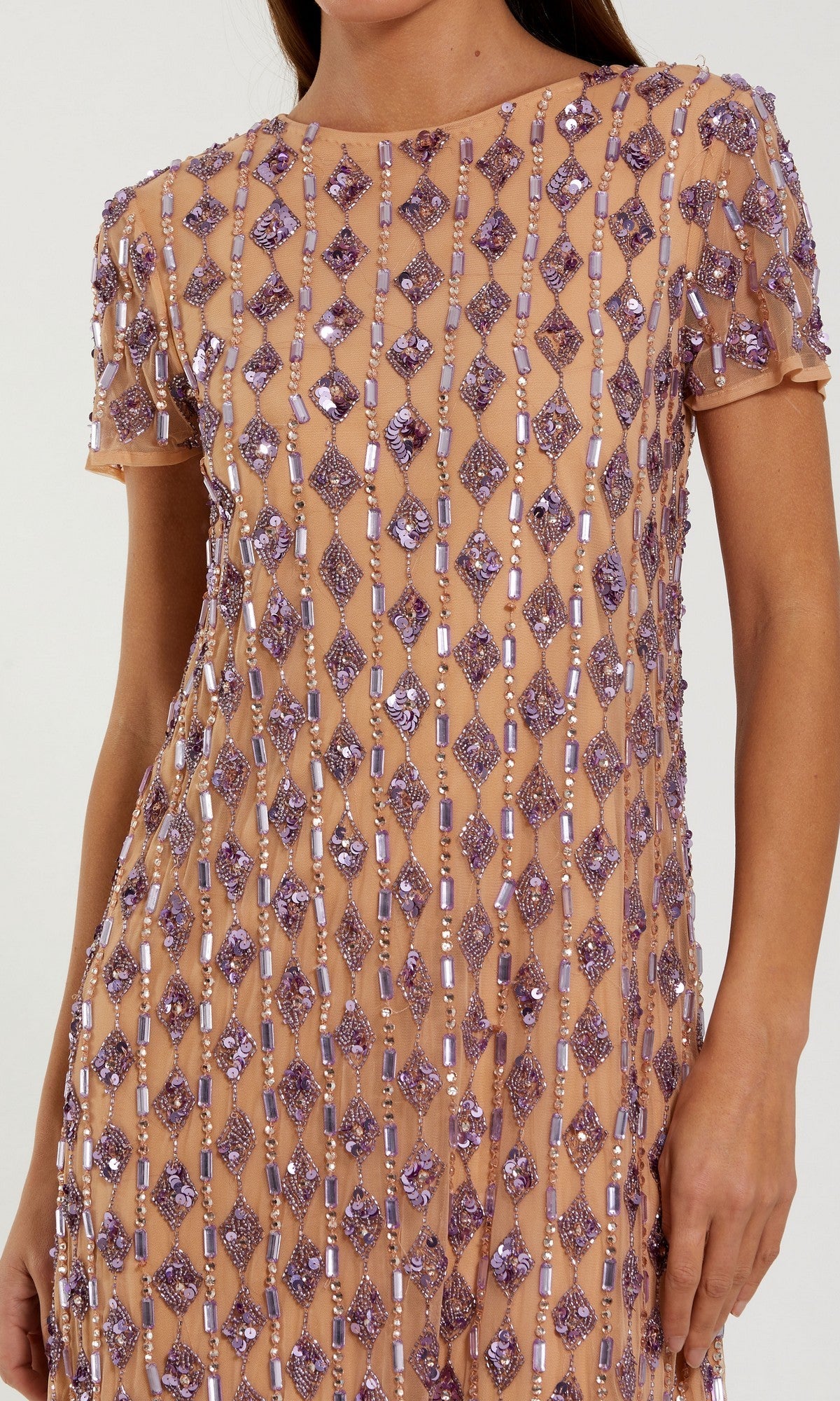 A person wearing the Mac Duggal 94292 Knee-Length Party Dress, a short-sleeved nude shift dress decorated with vertical rows of purple beads and sequins.