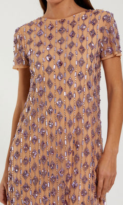 A person wearing the Mac Duggal 94292 Knee-Length Party Dress, a short-sleeved nude shift dress decorated with vertical rows of purple beads and sequins.