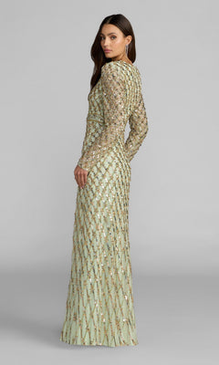 A woman wearing the Mac Duggal 94318 long formal dress in sage green, featuring full-length coverage, long sleeves, and gold embellishments, stands turned slightly to the side against a plain gray background.