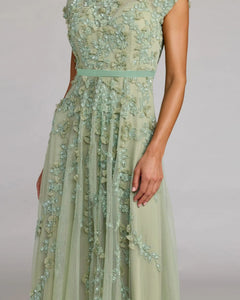 A woman models the Mac Duggal 94339 midi wedding guest dress, featuring light green cap sleeves, floral embroidery, embellishments, and a fitted waist, standing before a plain background.