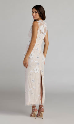 A woman wearing the Mac Duggal 9465 Long Formal Dress—sleeveless, ankle-length, and white with delicate floral embroidery—stands in heels facing away, looking over her shoulder.