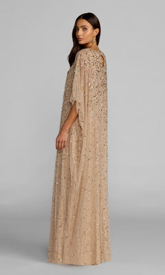 A woman models the Long Formal Dress: Mac Duggal 9475—a long, beige, sequin-beaded gown—standing sideways with her head turned toward the camera against a plain gray background.