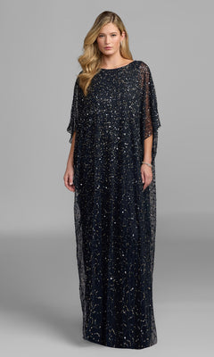 A woman stands against a plain gray background wearing the Long Formal Dress: Mac Duggal 9475, a loose-fitting, floor-length gown in Midnight Gold featuring shimmering sequin details.