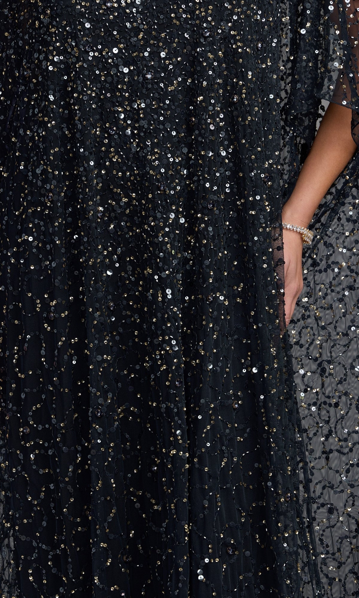 Close-up of the Mac Duggal 9475 Long Formal Dress, adorned with glimmering sequins and intricate beadwork; a woman’s arm appears on the right, accessorized with a gold bracelet—an exquisite choice for an elegant mother-of-the-bride gown.