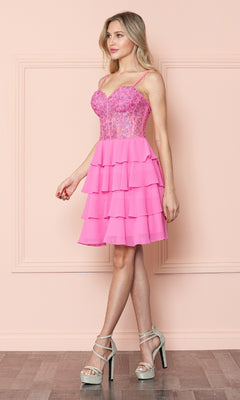 A woman in the Poly USA 9494 Short Ruffled Lace-Up Hoco Dress with a corset bodice and spaghetti straps stands against a light pink wall, styled with silver high-heeled sandals.