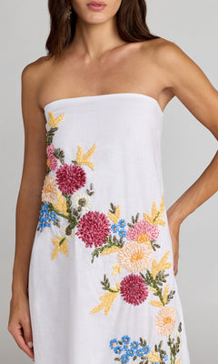 A woman wears the Mac Duggal 9498 long strapless linen dress, adorned with vibrant pink, yellow, blue, and green floral embroidery.