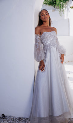 A woman in the Eureka 9505 Long Sleeve Strapless Long Prom Gown, featuring an embroidered sweetheart bodice and detachable balloon sleeves, poses by a curved white wall in a sunlit outdoor setting.