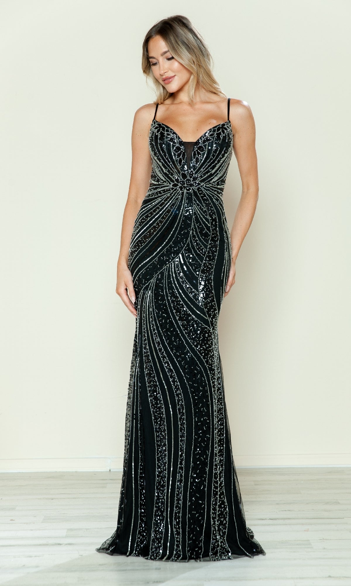 A woman models the Beaded Spaghetti-Strap Prom Gown (Poly USA 9510) in black/silver, featuring silver sequin patterns, against a light backdrop for an elegant formal look.