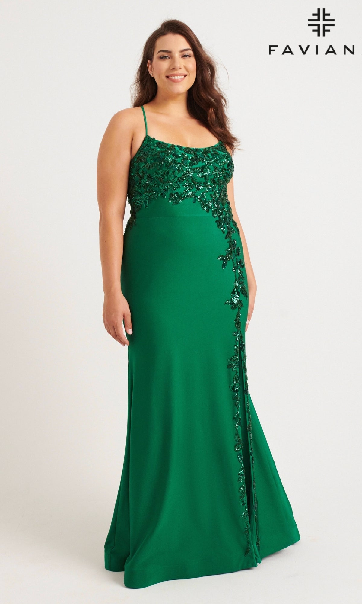A woman models the Faviana 9570: a plus-size, strappy, floor-length green prom dress with sequin floral designs, standing against a white background. 