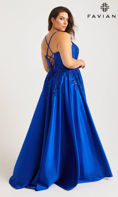 Model wears the Faviana 9575, a long plus-size royal blue prom dress with floral embroidery and lace-up back, looking over her shoulder; Faviana logo displayed in the top right corner.