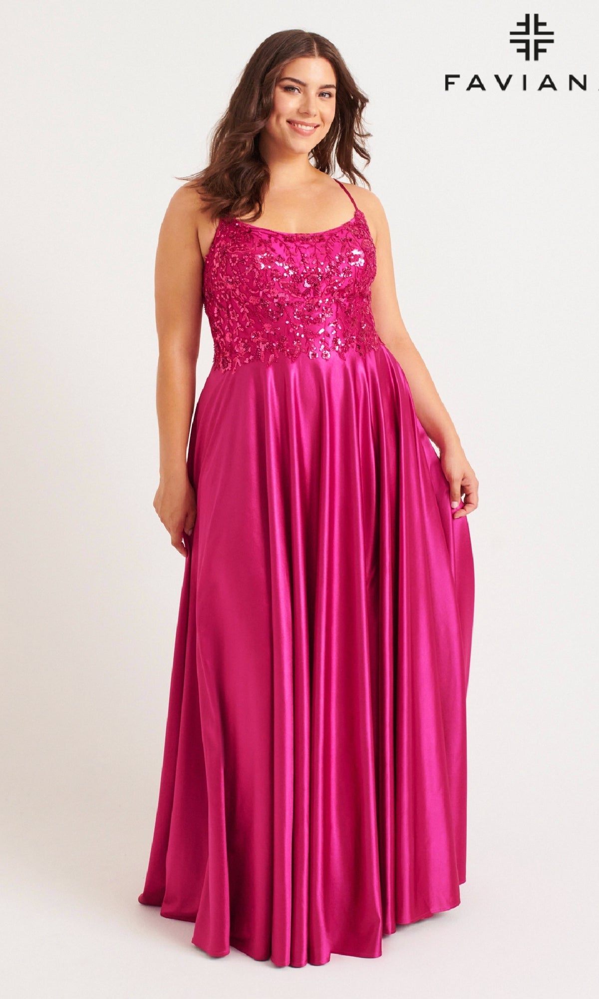 A woman in a sleeveless, floor-length magenta Faviana 9582 plus-size prom dress with a beaded bodice and pockets stands against a plain background, with the 