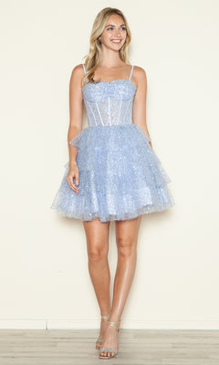 A woman stands against a plain wall wearing the Short Sequin Ruffled Fit-and-Flare Hoco Dress 9546 in light blue with spaghetti straps, paired with clear high-heeled sandals.