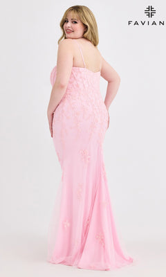 A woman in the Faviana 9604 Plus-Size Beaded-Lace Prom Gown, a light pink, floor-length dress with thin straps, stands facing backward and looks over her shoulder. The plain white backdrop displays the Faviana logo in the top right corner.