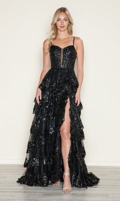 A woman stands indoors wearing the Poly USA 9606 long prom dress, featuring black sequins, ruffled tiers, a high slit, thin straps, and paired with silver open-toe heels.