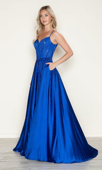 A woman stands against a plain wall wearing the Poly USA 9610 long prom dress, featuring a bright blue, floor-length A-line silhouette with spaghetti straps and subtle beading embellishments.