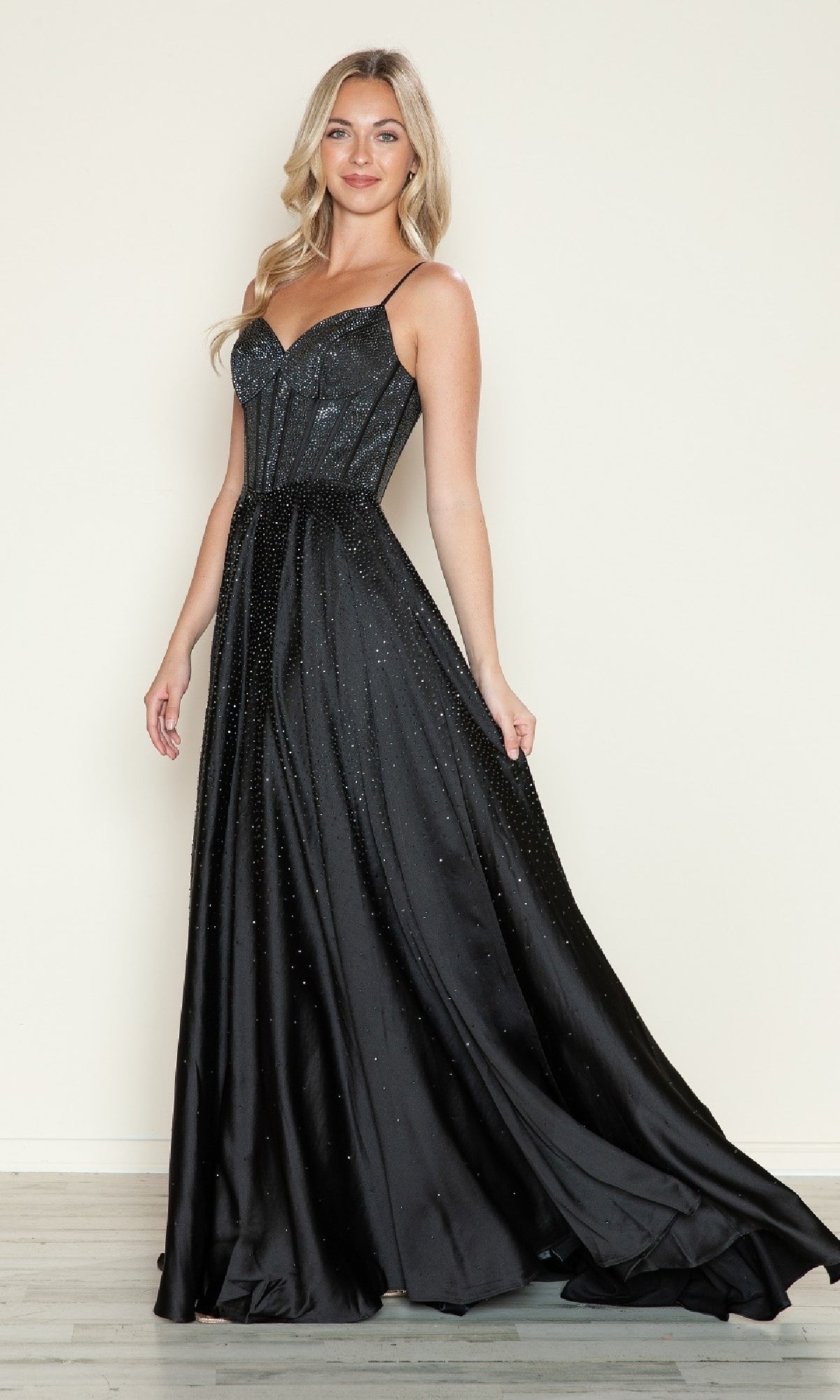A woman wearing the Poly USA 9610 Long Prom Dress, a sleeveless black gown with a corset bodice and subtle sparkling beading, stands against a plain background.