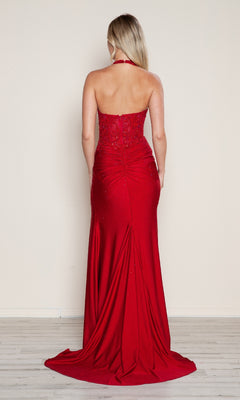 A woman with long blonde hair models the Poly USA 9614 long prom dress—floor-length, strapless, vibrant red with a high leg slit—as she faces away on a light wood floor against a plain beige wall.