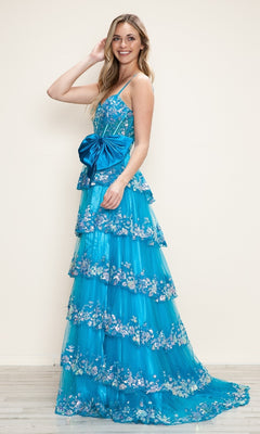 A woman smiles against a plain light background, wearing the Long Prom Dress: Poly USA 9626 in bright blue—an A-line gown with tiered skirt, spaghetti straps, and a large bow at the waist.