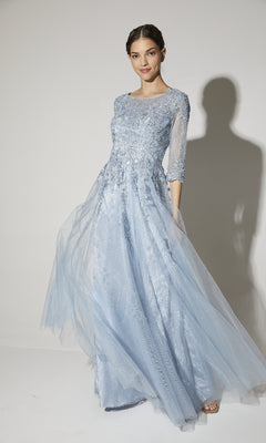 A woman models the Eureka 9660, a flowy long sleeve formal dress with a light blue lace bodice and sheer sleeves, posed against a plain background.