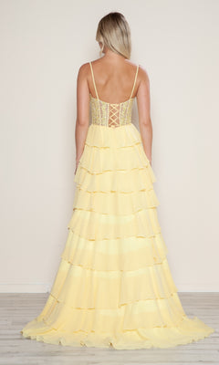Woman with her back to the camera wears the Poly USA 9698 Long Tiered Corset Prom Dress, featuring a light yellow A-line silhouette, spaghetti straps, and lace-up corset-style bodice detail at the back.