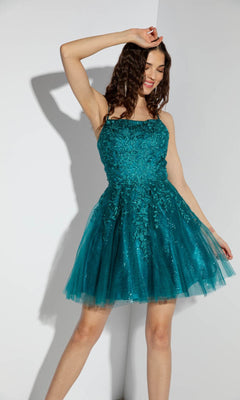 A woman wearing the Eureka 9727 Lace-Up Short Prom Dress poses against a white wall.