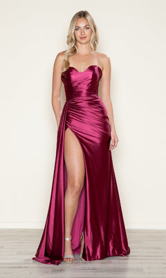 A woman in the Strapless Side-Sash Long Prom Gown (Poly USA 9734)—a magenta, strapless, floor-length satin dress with a thigh-high slit—stands on a light wood floor against a beige background. This elegant gown is under $200.