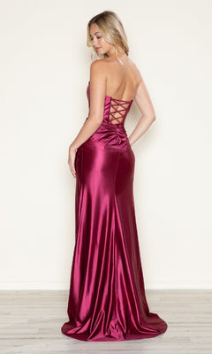 A woman faces away on a light wood floor wearing the Strapless Side-Sash Long Prom Gown: Poly USA 9734, a shiny burgundy satin evening dress with a sweetheart neckline and lace-up back—an elegant choice for under $200.