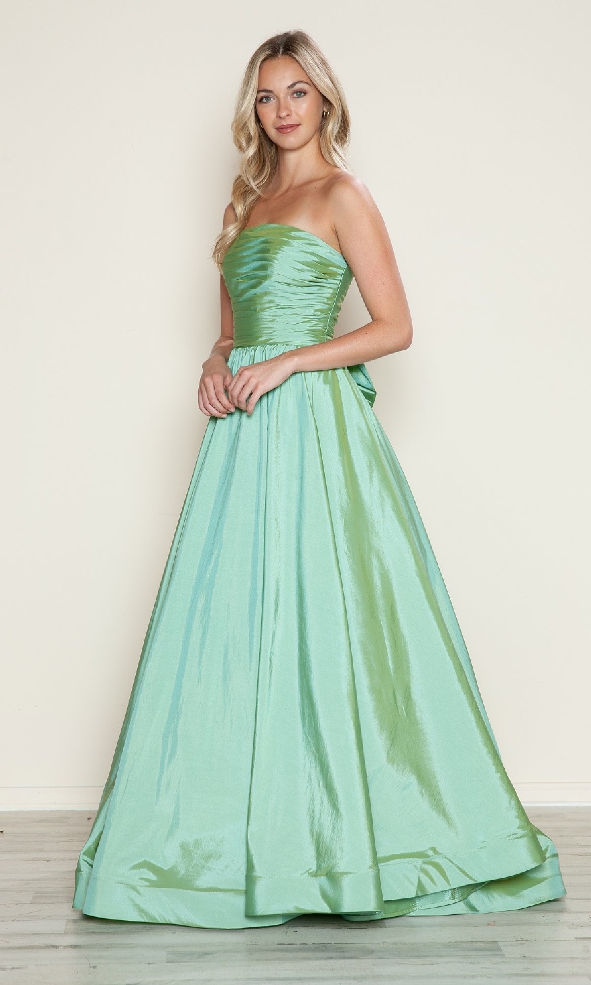 A woman models the Long Prom Dress: Poly USA 9754, a strapless, floor-length taffeta gown with a ruched bodice and adjustable lace-up back, shimmering in light green against a plain background.