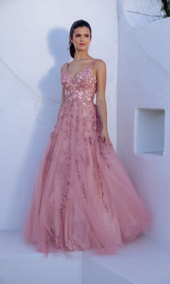 A woman stands against a white wall, wearing the Eureka 9858 Embroidered-Lace Long Prom Dress in pink, featuring a sleeveless A-line design with floral embroidery and a flowing tulle skirt.