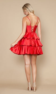 A woman wearing the Poly USA 9896 Lace-Up Short Ruffle Hoco Dress with a beaded corset bodice and lace-up back stands facing away, holding the edge of her fit-and-flare cocktail dress and wearing clear high heels.