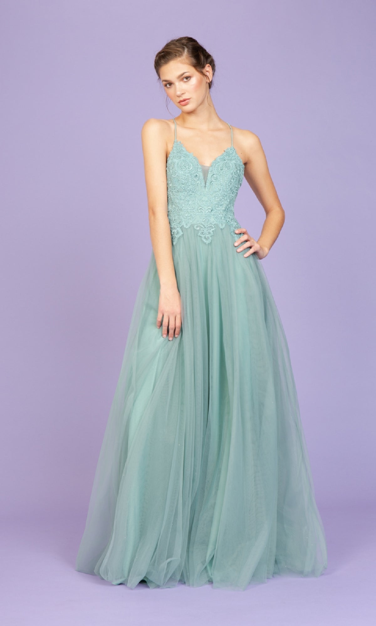 A woman wears the Lace-Bodice Long Glitter Prom Dress: Eureka 9902, a light teal, floor-length gown with lace bodice, tulle skirt, and thin straps, posing against a plain lavender background.