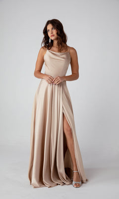 A woman stands against a plain light background wearing the Eureka 9916 cowl-neck, sleeveless, floor-length satin formal dress in champagne with a thigh-high slit.