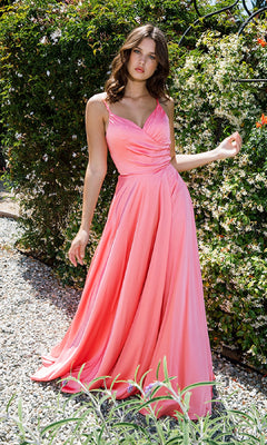 A woman stands outdoors on a gravel path beside bushes, wearing the Classic Long Satin Prom Dress: Eureka 9917—a sleeveless, floor-length pink gown with a fitted bodice and flowing skirt.