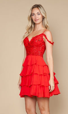 A woman wears the Poly USA 9920 short homecoming dress, a sleeveless red fit-and-flare style with a lace bodice and tiered ruffle skirt, standing against a beige background.