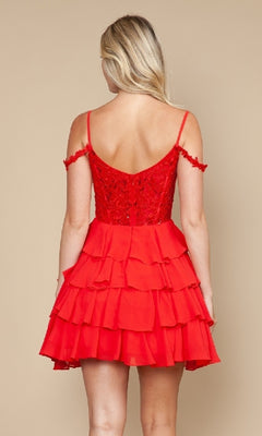 A woman faces away wearing the Poly USA 9920 short homecoming dress, featuring a red fit-and-flare silhouette, fitted lace bodice, off-the-shoulder straps, and tiered ruffled skirt against a plain beige background.