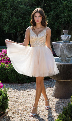 A woman in the Glitter-Bodice Short A-Line Hoco Dress (Eureka 9926), featuring a sleeveless, sequin bodice, stands outdoors near a stone fountain surrounded by lush greenery.