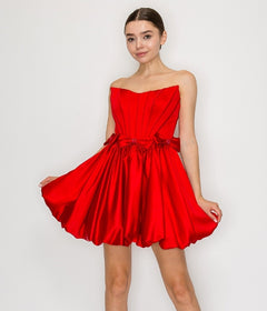 A woman models the Poly USA 9950 Strapless Short Bubble Party Dress in red, featuring a corset-style bodice and flared skirt, standing against a plain white background.