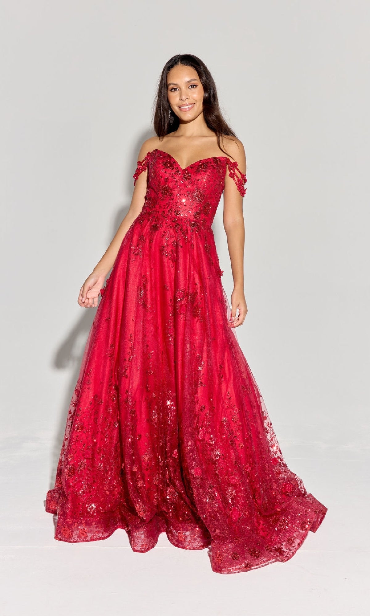 A woman poses against a light background in the Eureka 9980 Long Glitter-Tuller A-Line Prom Dress, a red, off-the-shoulder, floor-length gown adorned with floral embellishments.