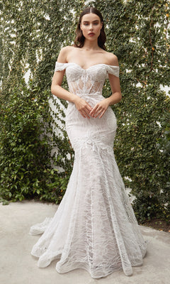 A woman in the Off-the-Shoulder Long White Lace Prom Gown with a mermaid silhouette poses gracefully before a vine-covered wall.