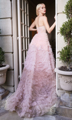 A woman stands in an open doorway, facing away, wearing the Tiered Strapless Ombre Pink Prom Ball Gown A0767. The light pink ruffled tiers and long train create a graceful silhouette ideal for formal events.
