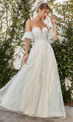 A woman stands outdoors before a leafy green wall, wearing the Strapless Puff-Sleeve Long Prom Ball Gown A1046, a white dress featuring sparkly embroidered floral details and puff sleeves.