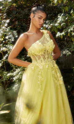 A woman stands outdoors in a garden, wearing the Sheer-Bodice One-Shoulder Prom Ball Gown A1140 in yellow, featuring floral embellishments and sheer panels.
