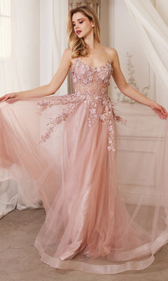 A woman stands indoors holding out the sides of the Flower-Embellished Long Tulle Prom Ball Gown A1142, a flowing blush pink dress with 3D floral details on the bodice and skirt and a sheer waist.