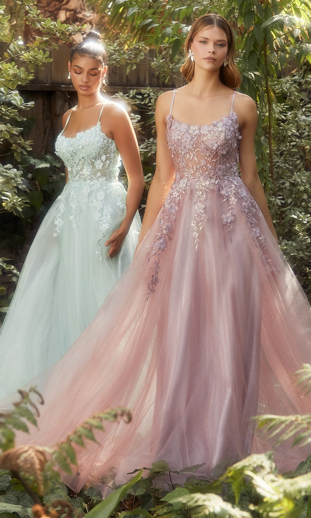 Two women stand outdoors in lush greenery wearing the Flower-Embellished Long Tulle Prom Ball Gown A1142, featuring pastel hues, 3D floral details, and sheer waists.