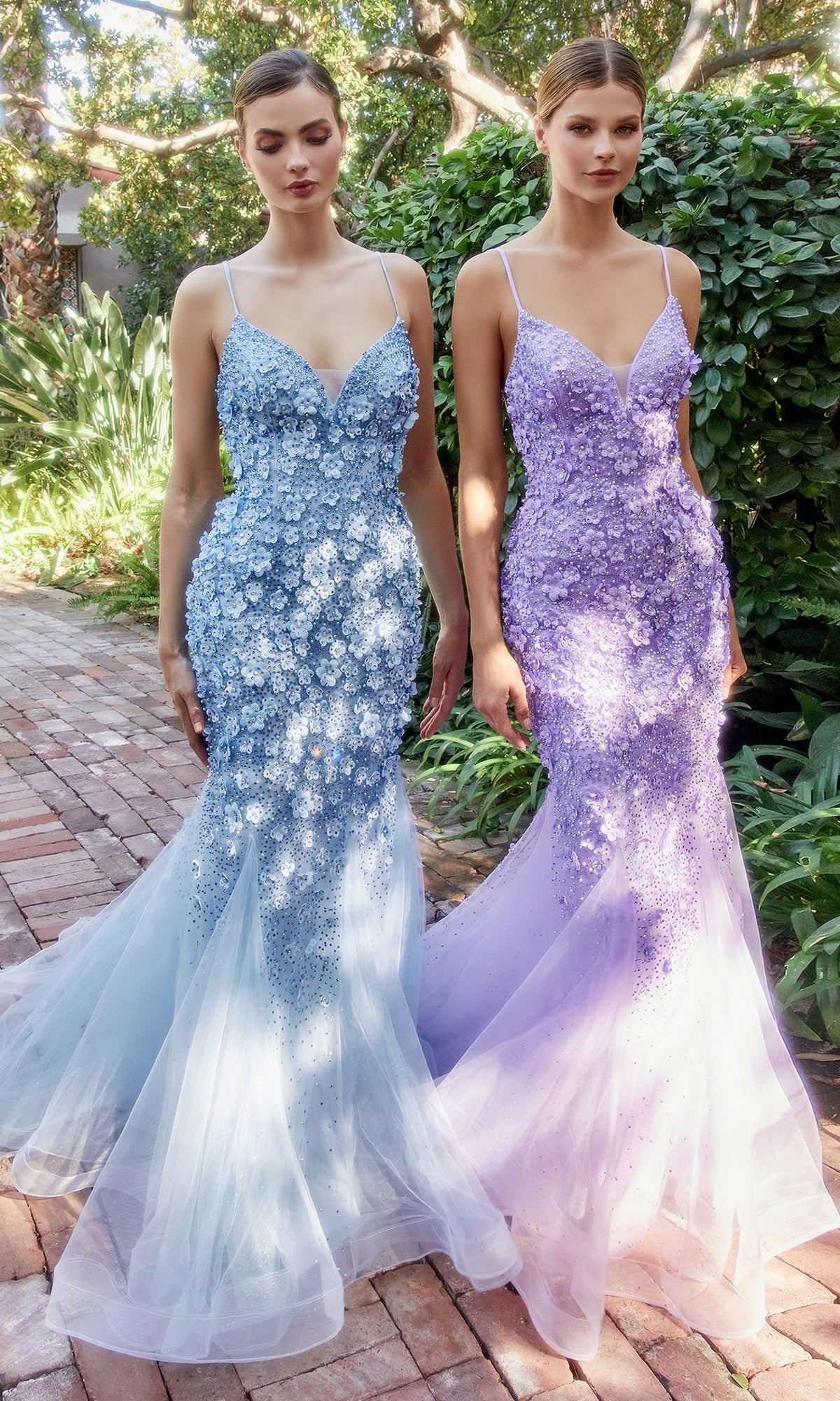 Two women stand outdoors in floor-length, mermaid-style Floral Beaded Long Mermaid Prom Dress A1201 gowns—one in blue, the other in lavender—featuring thin straps and beautiful 3-D floral appliques.