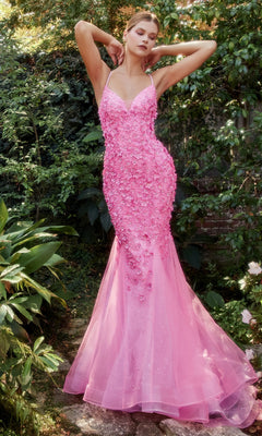 A woman stands in a garden wearing the Floral Beaded Long Mermaid Prom Dress A1201, a fitted, floor-length gown with 3-D floral appliques and a dramatic tulle skirt.