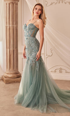 A woman in the Andrea and Leo A1232 long lace mermaid prom dress, featuring a strapless, fitted, pale blue-green bodice and sheer tulle skirt, stands in an elegant classical-style room.