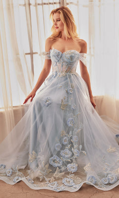 A woman wearing the Long Blue Prom Ball Gown, Andrea and Leo A1246, with floral embroidery sits by sheer curtains, gazing to the side.
